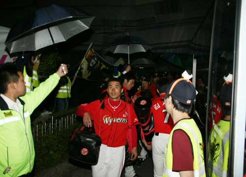 7일 부산 사직야구장에서 열린 2009 프로야구 롯데 자이언츠-SK 와이번스 경기 후 롯데에 1점차로 패배한 SK 선수들이 경찰과 경호요원들의 우산 ‘호위’를 받으며 버스에 오르고 있다. 이날 경찰은 6일보다 2개 중대가 많은 5개 중대의 병력을 배치해 롯데 팬들의 접근을 원천봉쇄했다. 