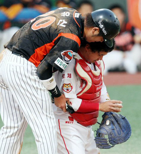   8일 광주무등경기장에서 벌어진 2009 프로야구 KIA 타이거즈와 롯데 자이언츠의 경기에서 2회초 2사 2루 주자였던 롯데 포수 강민호가 홈으로 쇄도하다 KIA 포수 차일목의 블로킹에 아웃되고 나서 차일목에게 다가가 사과하고 있다. 