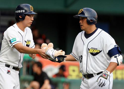 22일 서울 잠실야구장에서 열린 2009 프로야구 두산 베어스-롯데 자이언츠 경기, 두산 김동주(오른쪽)가 1회말 1점 홈런을 친 후 홈을 밟으며 곰인형을 받고 있다. 
