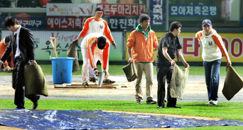 13일 오후 인천 문학구장에서 열린 프로야구 플레이오프 5차전 두산 베어스-SK 와이번스의경기. 2회 소낙비로 경기가 중단되자 관계자들이 스폰지 등으로 물을 제거하고 있다. 