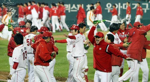 24일 오후 서울 잠실야구장에서 열린 2009 프로야구 한국시리즈 7차전 기아 타이거즈-SK 와이번스 경기 후, 우승을 차지한 기아 선수들이 샴페인을 터뜨리며 환호하는 가운데 SK 선수들이 쓸쓸하게 덕아웃으로 들어가고 있다. 