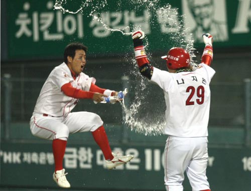 24일 오후 서울 잠실야구장에서 열린 2009 프로야구 한국시리즈 7차전 기아 타이거즈-SK 와이번스 경기 후, 끝내기 홈런을 친 기아 나지완이 팀 동료의 물세례 속에 환호하고 있다. 